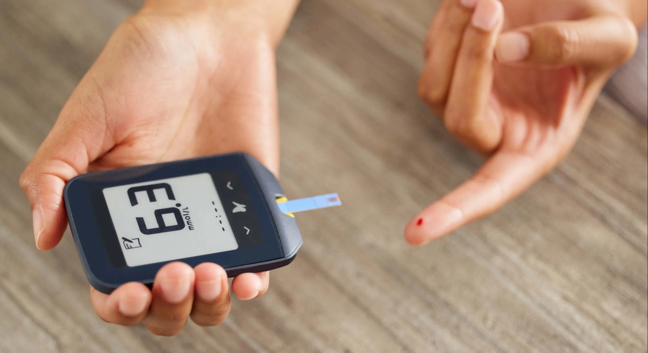 Lector de glucosa y dedo con gota de sangre para medir el nivel de azúcar en diabetes