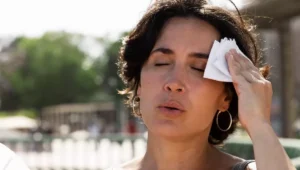 Mujer con calor en verano sudando y secándose la frente, situación relacionada con diabetes