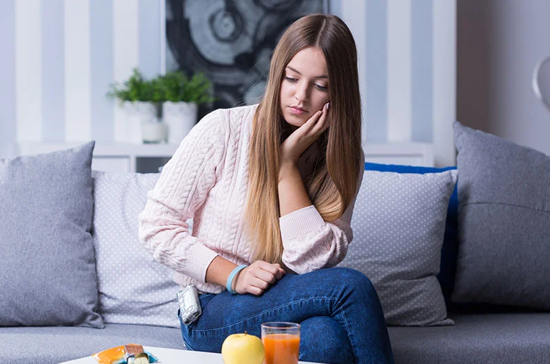Persona sentada en un sofá con expresión de frustración por cambios en los niveles de glucosa en diabetes